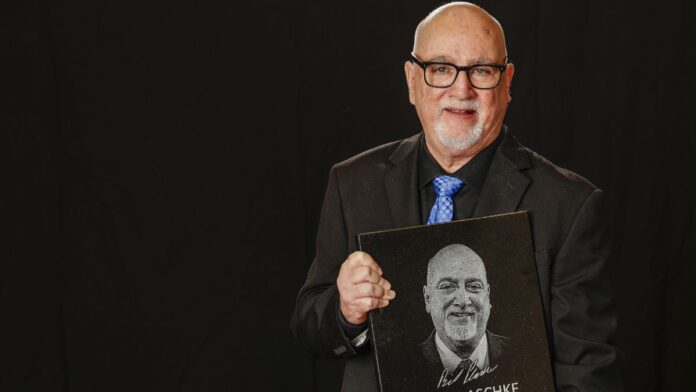 Bill Plaschke holding his book